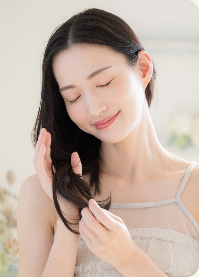 髪に触れて微笑む女性