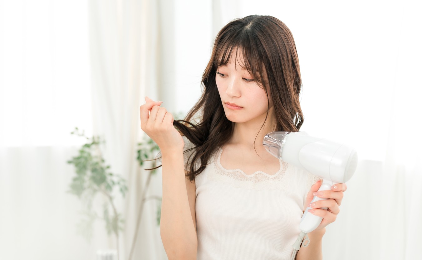 ドライヤーで髪を乾かす女性